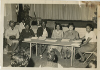 Photo of women around a table in auditorium