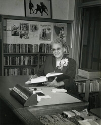 Susan Dart Bulter seated at Circulation desk, Dart Hall Branch Library