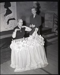 Two Women Posing Near a Table Decorated with Flowers