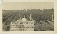 Young Girls with Potato Variety Test Sign in Field