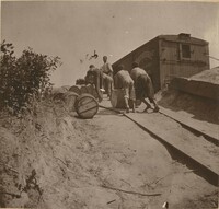 Men rolling barrels toward train