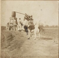 Two women, child and dog near well