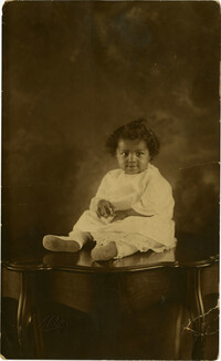 Formal portraint of infant sitting on table