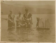 Children in swimsuits with model boat