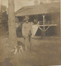 Pauline Donner with gun and dog in front of Main house
