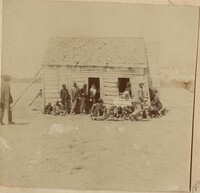Fourteen people in front of a leaning cabin